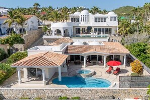 A large villa with a swimming pool, outdoor seating, and a covered patio area.