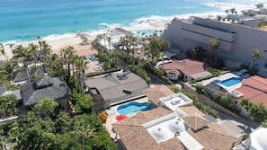 Un resort con piscina, playa y palmeras.