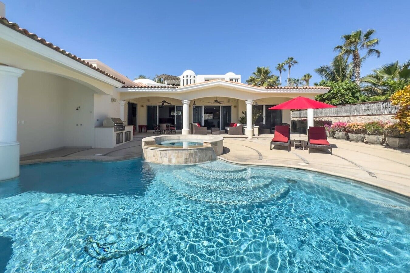 A swimming pool with a hot tub, lounge chairs, and a covered patio area.