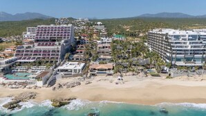 A coastal hotel with multiple buildings, a beach, and a pool area.