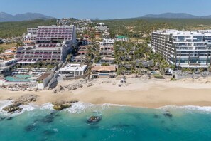 A coastal hotel with multiple buildings, a beach, and a pool area.