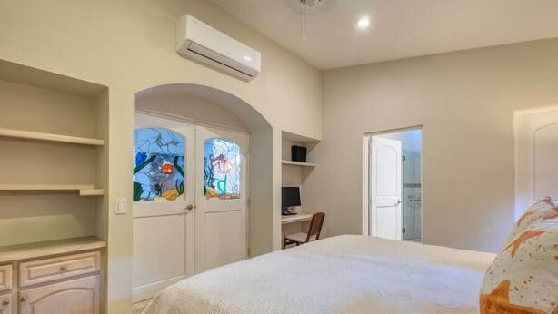 A bedroom with a bed, a desk, a chair, and a shower area.