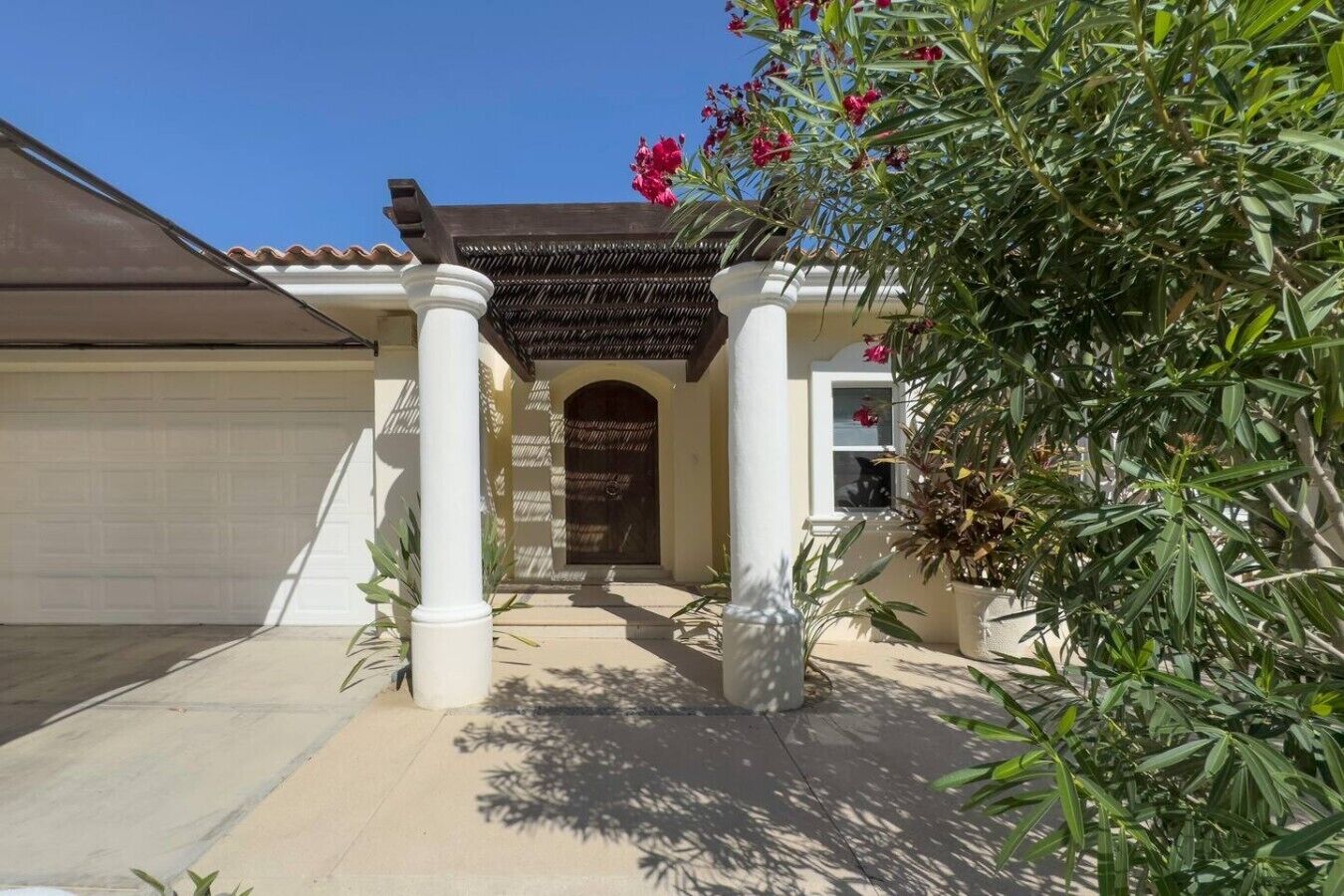 A residential property with a covered entryway, a garage, and a well-maintained garden.