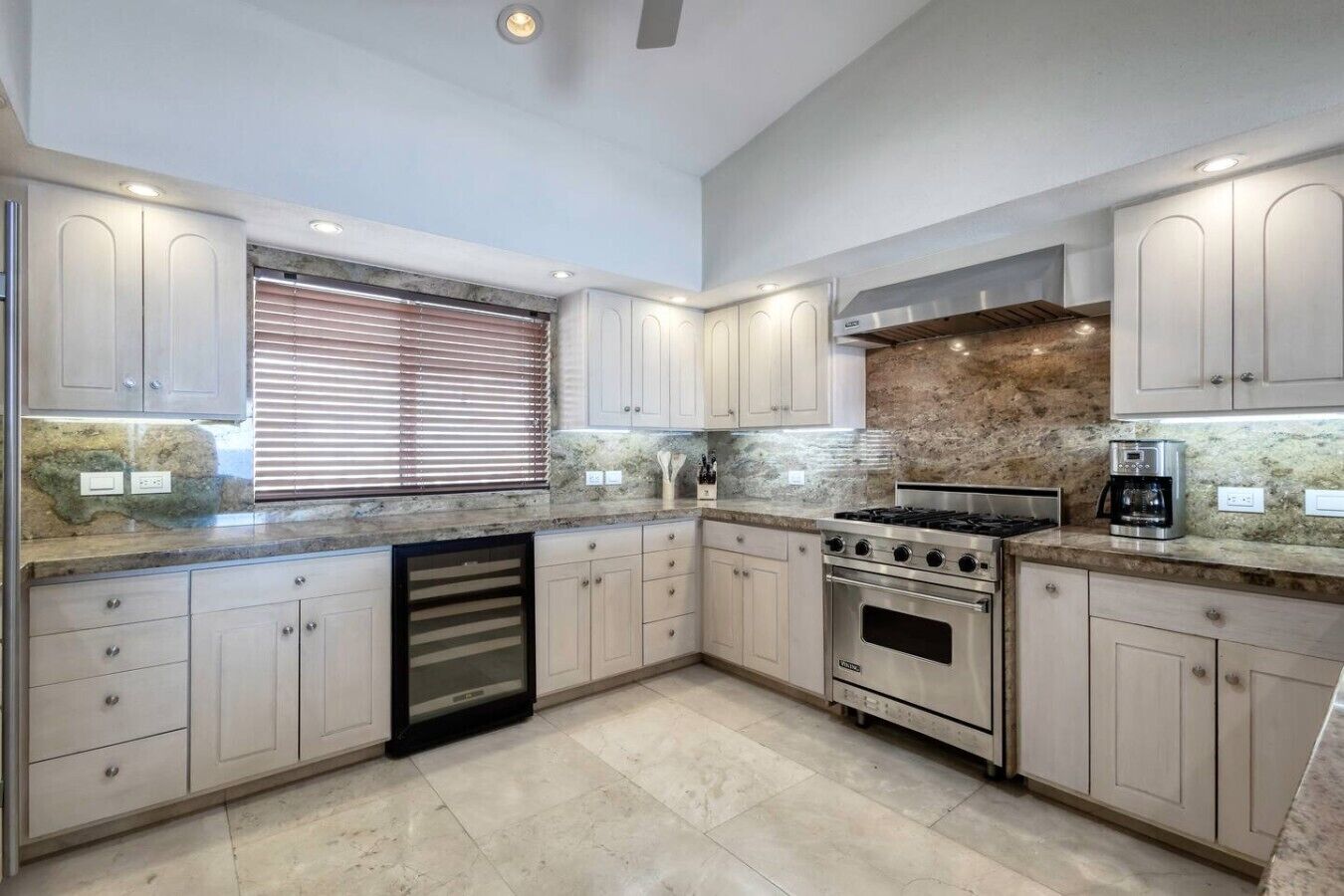 A modern kitchen with granite countertops, stainless steel appliances, and light-colored cabinetry.