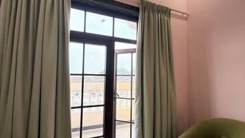 Una habitación con un ventanal grande, un equipo de aire acondicionado y un sofá verde.