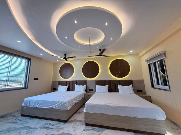 A modern bedroom with two beds, circular wall lighting, ceiling fans, and a large window.