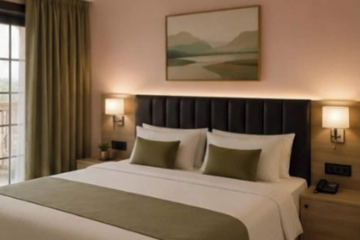 Habitación de hotel con una cama grande, dos lámparas de noche, una mesita de noche y un cuadro en la pared.