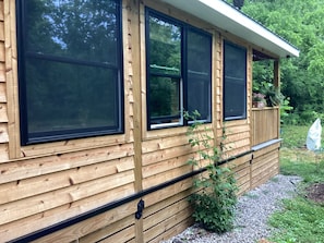 Eine Holzhütte mit großen Fenstern, einer Holzterrasse und einem Garten.