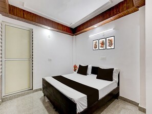 A bedroom with a bed, a wardrobe, and a wall with three framed pictures. - Super Collection O Sector 18 (Noida)