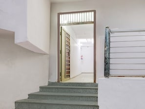A staircase leading to a room with a window, a door with a metal gate, and a fire extinguisher on the wall. - Super Collection O Sector 18 (Noida)