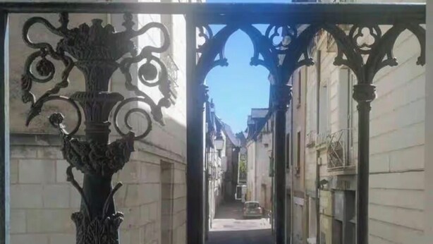 A narrow street with ornate metal gates and buildings on either side.
