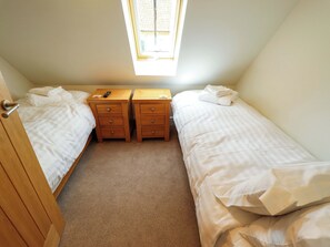 Ein Schlafzimmer mit zwei Einzelbetten, einem Holznachttisch mit Schubladen, einer Fernbedienung und einem Fenster mit Blick.