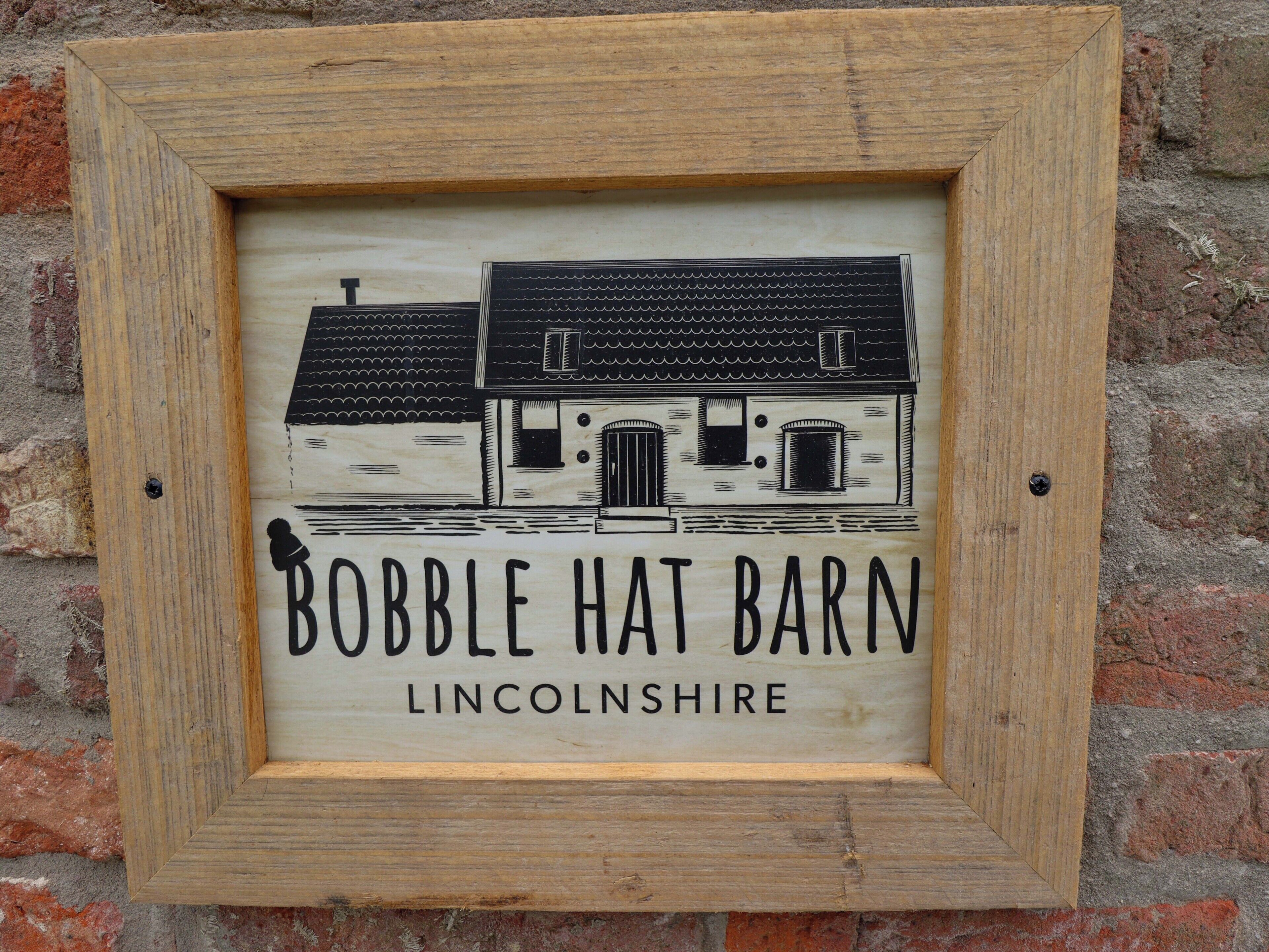 Ein gerahmtes Schild mit einer Illustration eines Hauses und dem Text 'BOBBLE HAT BARN LINCOLNSHIRE'.