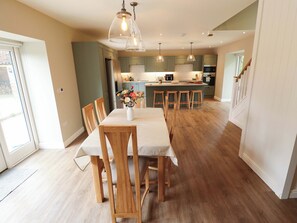 A modern kitchen with wooden cabinets, a central island, and pendant lighting. - Bobblehat Barn (Alford)
