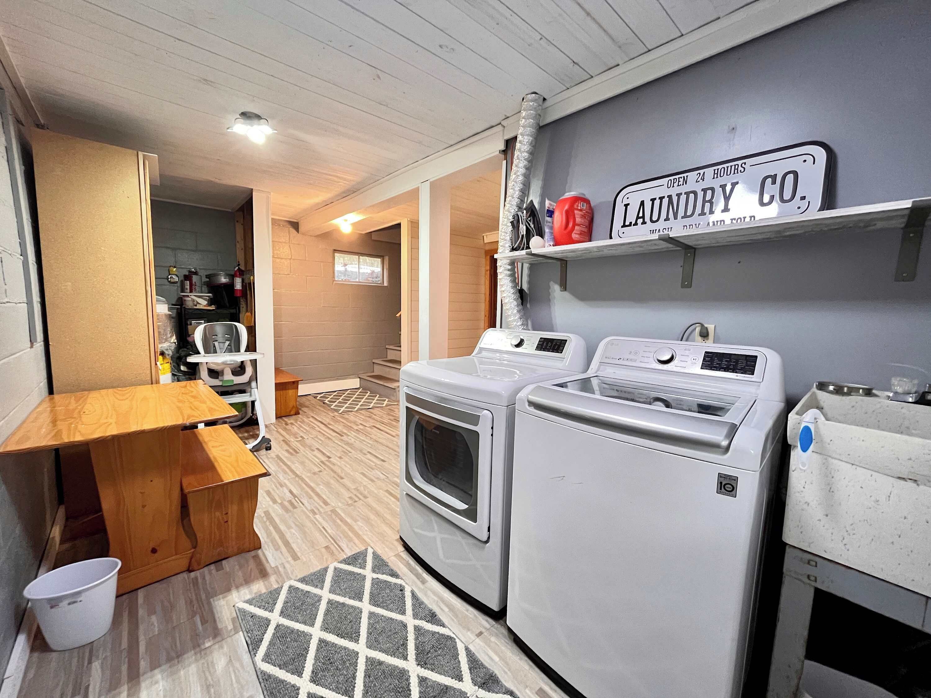 A laundry area with two washing machines, a wooden table, and a sign indicating 24-hour service.