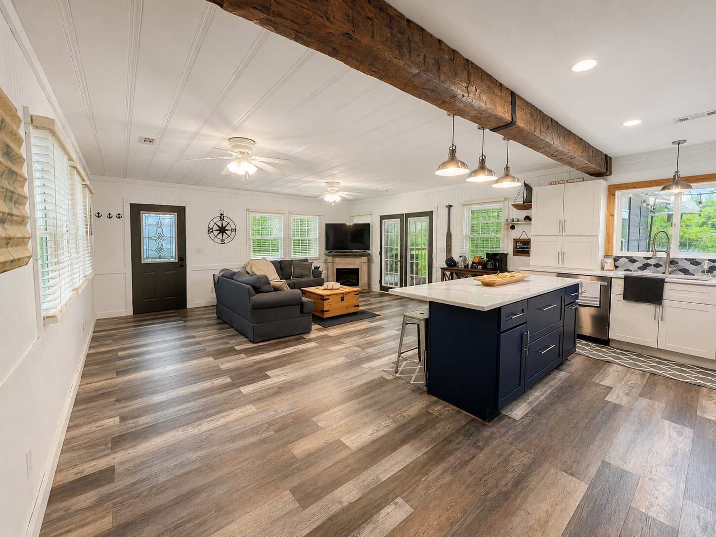 A spacious living area with a dark blue sofa, a fireplace, and a kitchen with a large island.