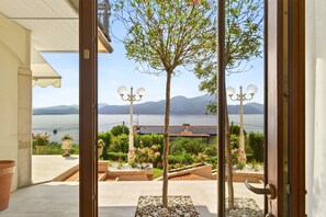 Ein Balkon mit Blick auf einen See und Berge, mit Kübelpflanzen und einer Laterne.