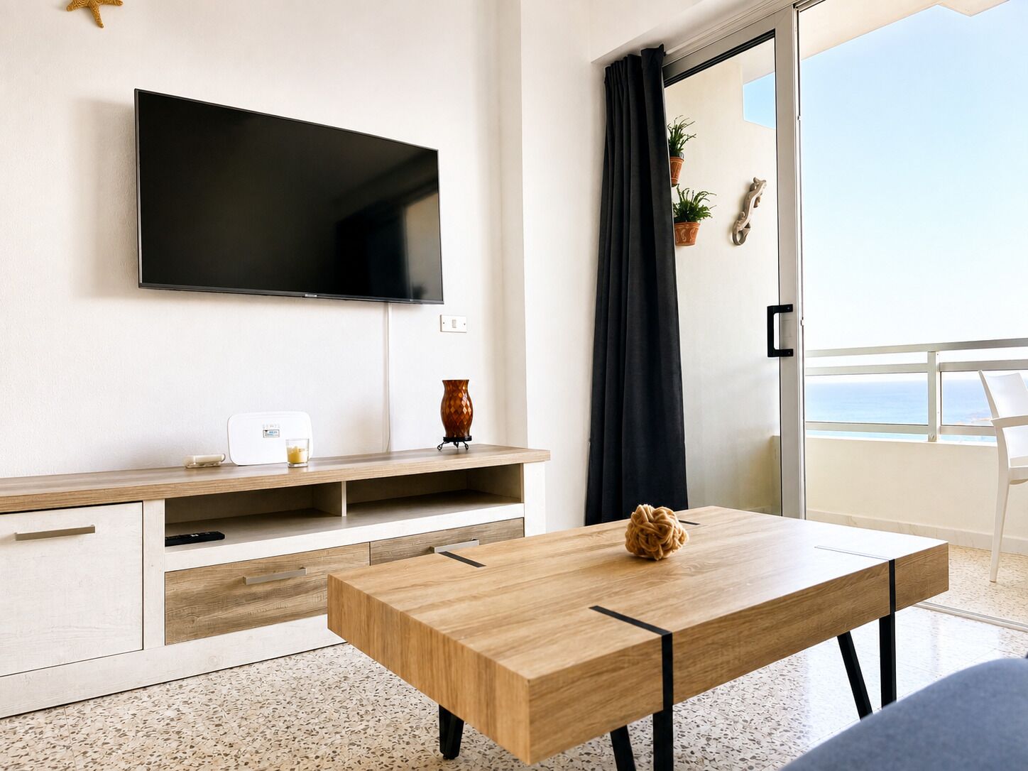En moderne stue med et fladskærms-tv, et træ sofabord og en balkon med udsigt.