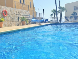 Ein Swimmingpool mit Steinmauer, Rettungsboje und Liegestühlen.