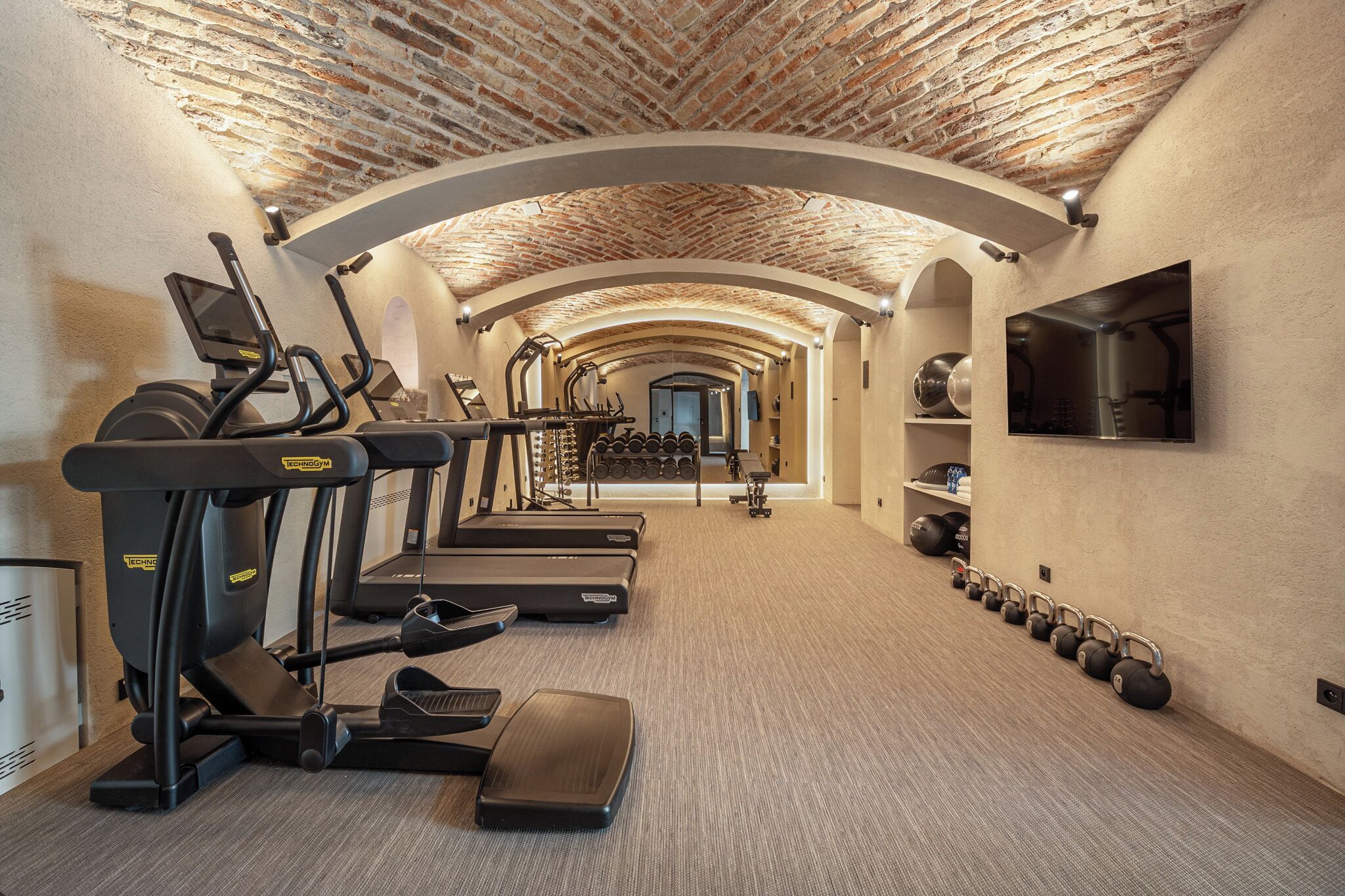 Un gimnasio con cintas de correr, máquinas de pesas y pesas sueltas.
