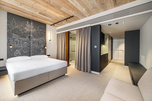 A modern hotel room with a large bed, a cityscape mural, a walk-in closet, and a separate seating area. - Origin Prague (Prague)