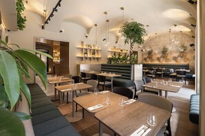 Un interior de restaurant modern amb taules, cadirees i una zona de bar.