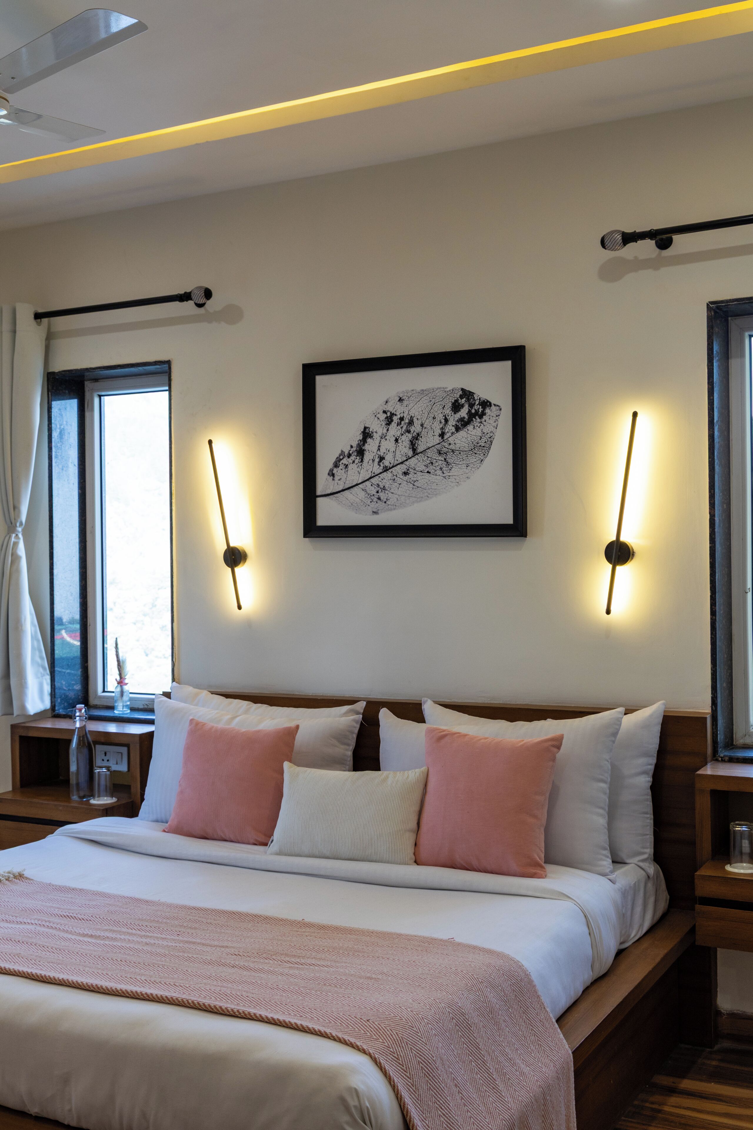 A bedroom with a bed, bedside tables, a window, and wall-mounted lights.