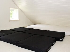 A room with a sloped ceiling, a small window, and two black mattresses. - 4 Star Holiday Home in Silkeborg (Silkeborg)
