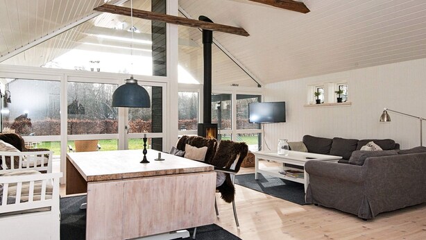 A spacious living area with a wooden floor, a large window, a fireplace, a television, and a sofa. - 4 Star Holiday Home in Silkeborg (Silkeborg)