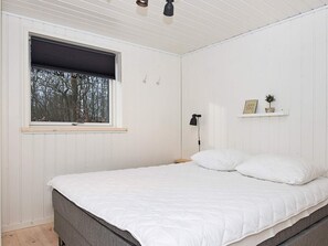 A bedroom with a bed, a window with blinds, a bedside lamp, and a shelf with decorative items. - 4 Star Holiday Home in Silkeborg (Silkeborg)