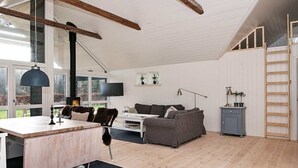 A spacious living area with a wooden floor, a dining table, a sofa, and a TV. - 4 Star Holiday Home in Silkeborg (Silkeborg)