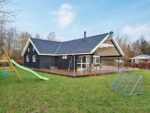 A modern house with a large deck, a play area with a slide, and a fenced yard. - 4 Star Holiday Home in Silkeborg (Silkeborg)