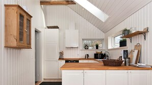 A kitchen with wooden cabinets, a window, and a built-in oven. - 4 Star Holiday Home in Silkeborg (Silkeborg)