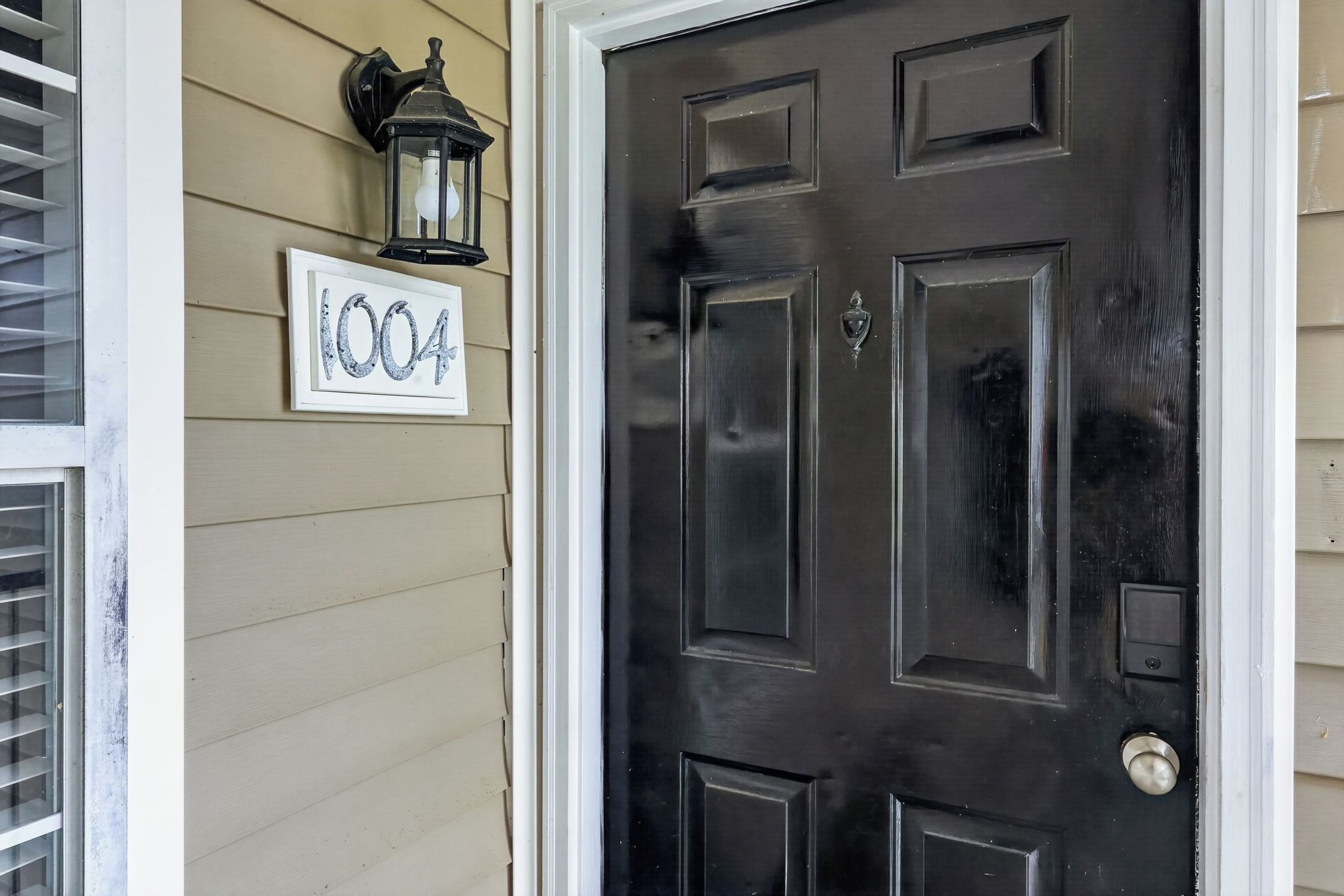 A black door with a number '1004' sign on the wall beside it.