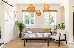 Ein gemütliches Wohnzimmer mit Sofa, Sessel, Couchtisch und hängenden Korblampen.