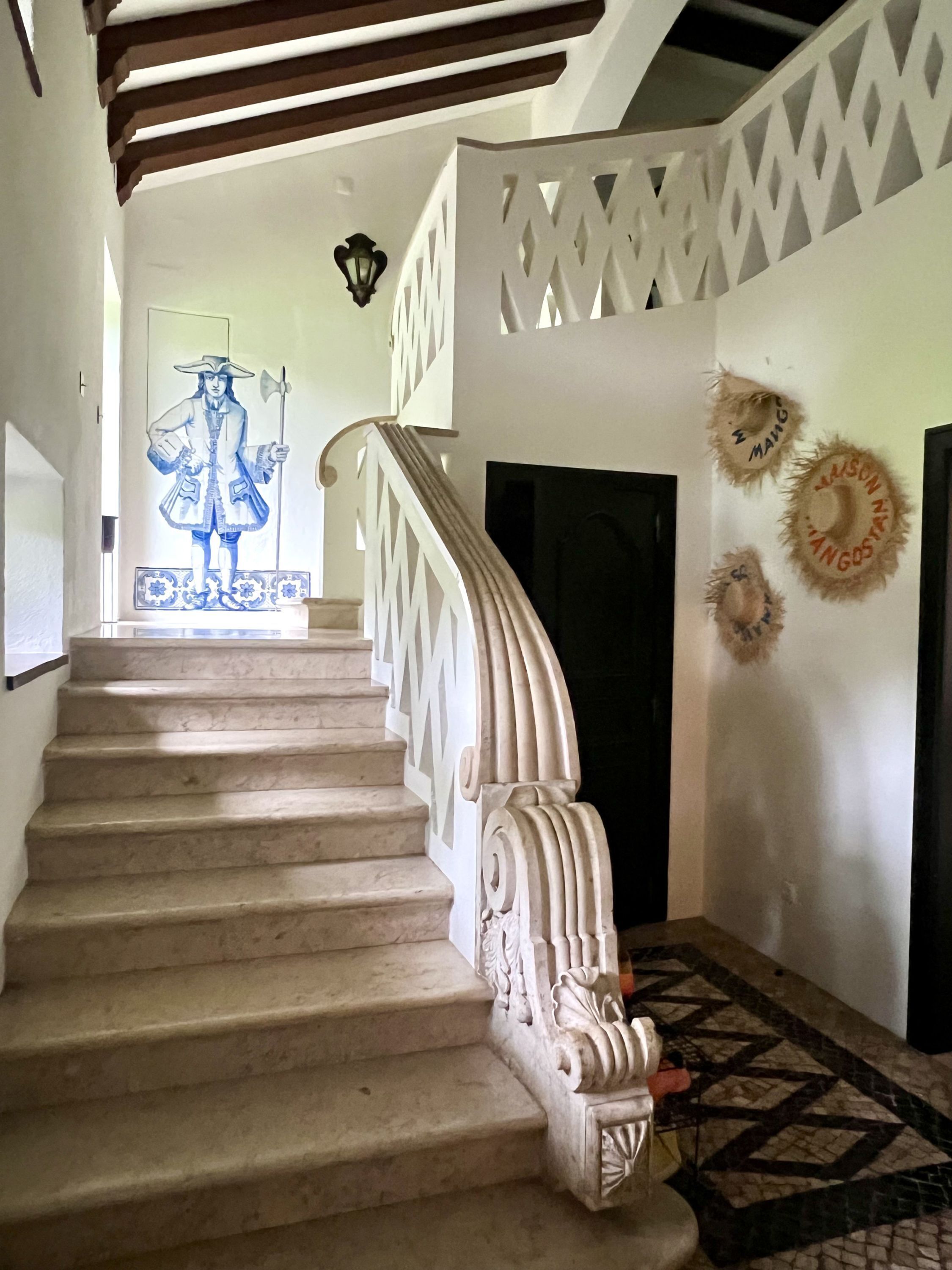 Eine Treppe mit aufwendiger weißer Geländerkonstruktion und einem gemusterten Boden.