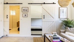 Quarto com cama, sofá, mesa de centro e luminária suspensa.