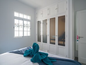 Ein Schlafzimmer mit einem Bett, einem Fenster und einem Schrank mit mehreren Türen.