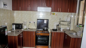 Una cocina con armarios de madera, estufa, microondas y lavamanos.