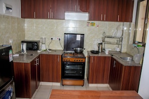 A kitchen with wooden cabinets, a stove, a microwave, and a sink.