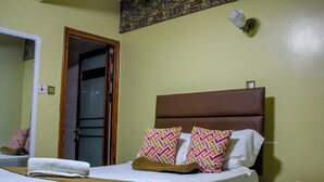 Una habitación de hotel con una cama, una mesita de noche, un espejo y una puerta.