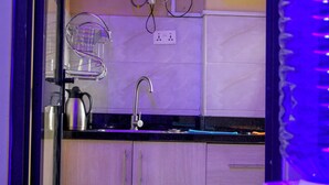 Una cocina con un lavamanos, una tetera y un enchufe.