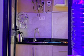 A kitchen with a sink, a kettle, and a power outlet.