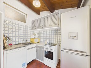 Eine Küche mit weißen Geräten, einer gefliesten Spritzschutzwand und Holzbalken an der Decke.