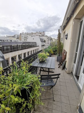 A rooftop terrace with a table and chairs, surrounded by potted plants and a view of the cityscape. - Stunning flat with terrasse - Trocadéro (Paris)