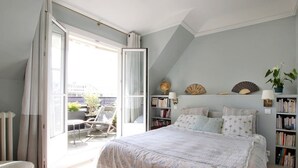 Une chambre avec un grand lit, un balcon, une bibliothèque et un globe terrestre.