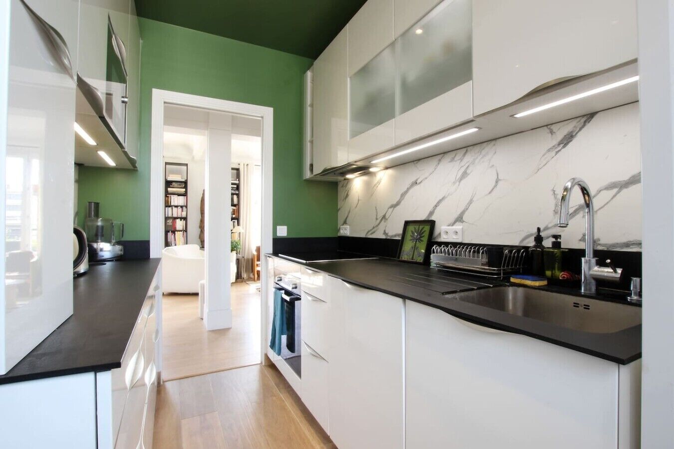 A modern kitchen with white cabinets, a black countertop, and a marble backsplash.