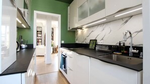 Une cuisine moderne avec des meubles blancs, un plan de travail noir et un pare-feu en marbre.