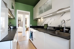 A modern kitchen with white cabinets, a black countertop, and a marble backsplash. - Stunning flat with terrasse - Trocadéro (Paris)