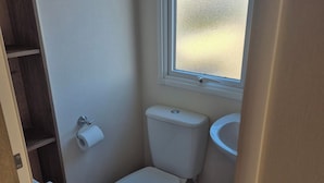 A small bathroom with a toilet, a sink, and a window.